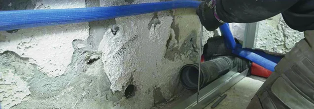 Person bringt Wasserwaage an Wand an